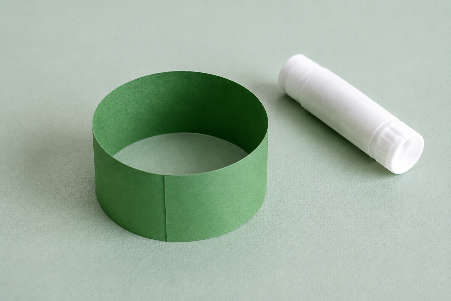 Een groene papierstrook is tot een ring gebogen; de uiteinden overlappen elkaar.