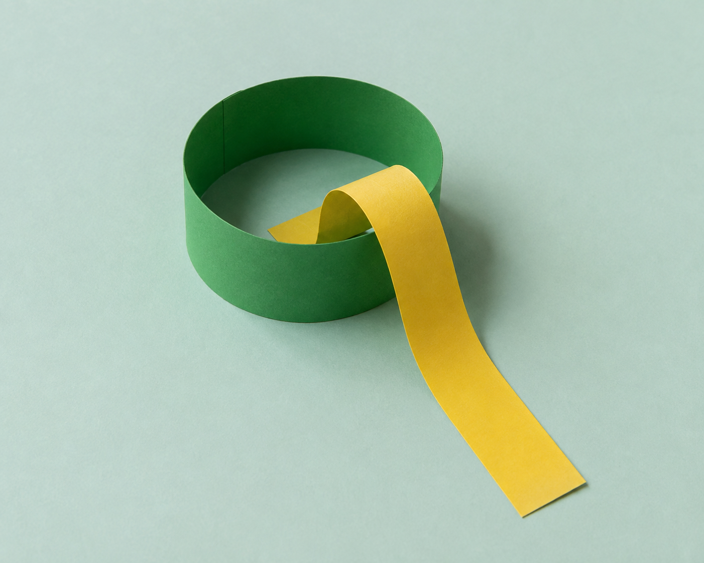 Een nog open gele papierstrook steekt door het gat van een gesloten groene ring.